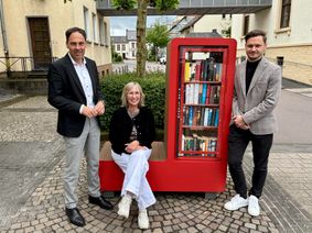 Von links: Bürgermeister Guido Wacht, Stadtbibliotheksleiterin Elisabeth Kurzmann und der Erste Beigeordnete Marcel Dawen eröffnen den neuen Bürgerschrank.