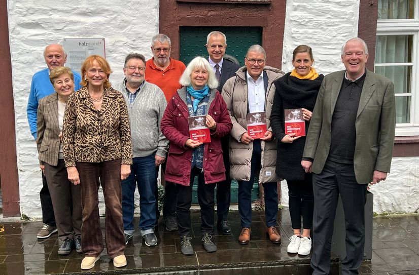 Der Vorstand des Geschichtsvereins des Monschauer Landes um Gabriele Harzheim (hinten, 3.v.r.), Vertreter der lokalen Politik und des Weiss-Verlags, präsentieren das neue »Heimatjahrbuch« vor dem Monschauer Stadtarchiv.
