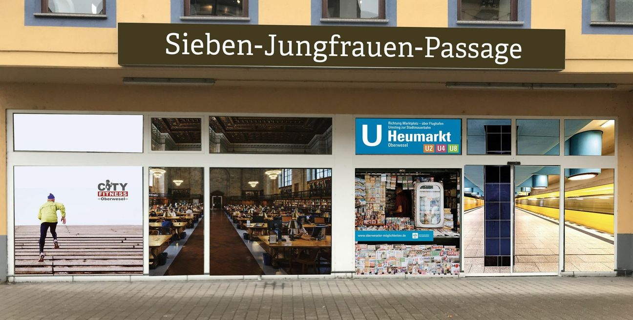 Neuer Name – neue Aktion: Statt leerer Fenster gibt es jetzt einen Kiosk, eine U-Bahn-Station mit Anschluss zur Stadtmauerbahn und eine Bibliothek – zumindest als Schaufensterbeklebung am ehemaligen Stadtmarkt in der Koblenzer Straße. (Foto: UfO)