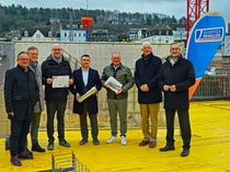 Vertreter von Stadt, der Volksbank Trier Eifel eG, des Landkreises Trier-Saarburg und der Stadtwerke Trier befüllen symbolisch eine Zeitkapsel, die im späteren Gebäude mit verbaut wird, mit aktuellen Tageszeitungen, Münzen und einer Urkunde zur Grundsteinlegung.