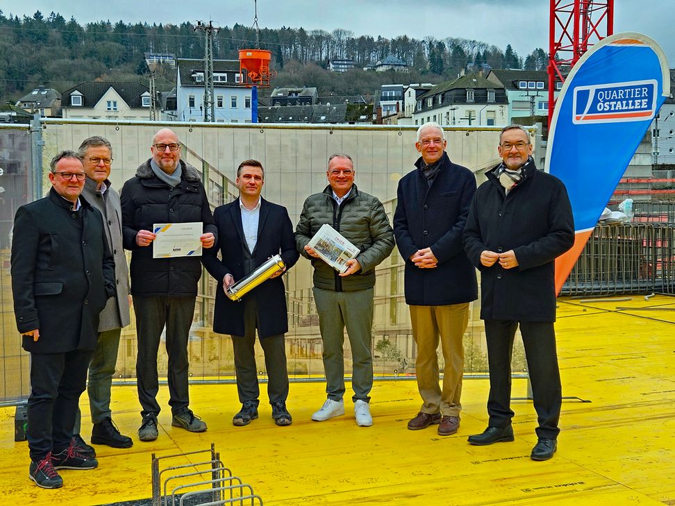 Vertreter von Stadt, der Volksbank Trier Eifel eG, des Landkreises Trier-Saarburg und der Stadtwerke Trier befüllen symbolisch eine Zeitkapsel, die im späteren Gebäude mit verbaut wird, mit aktuellen Tageszeitungen, Münzen und einer Urkunde zur Grundsteinlegung.