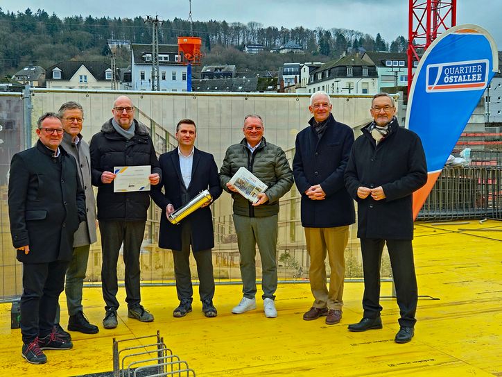 Vertreter von Stadt, der Volksbank Trier Eifel eG, des Landkreises Trier-Saarburg und der Stadtwerke Trier befüllen symbolisch eine Zeitkapsel, die im späteren Gebäude mit verbaut wird, mit aktuellen Tageszeitungen, Münzen und einer Urkunde zur Grundsteinlegung.