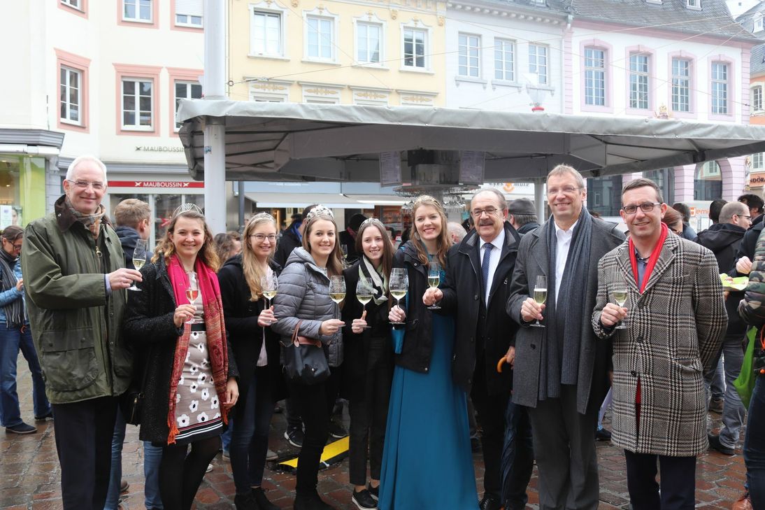 Freuen sich über die Eröffnung des Weinstandes (v.l.n.r.): Oberbürgermeister Wolfram Leibe; Mosel-Weinprinzessin Bärbel; Weinprinzessin Helene; Weinkönigin Celine und Weinprinzessin Anna von der Römischen Weinstraße; Saar-Obermosel-Weinkönigin Lena; Arnold Schmitt, der erste Kreisbeigeordneter des Landkreises Trier-Saarburg; ttm-Geschäftsführer Norbert Käthler sowie Kulturdezernent Thomas Schmitt. Foto: ttm GmbH