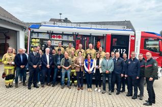 EU-Kommissarin Hadja Lahbib inmitten von NRW-Landwirtschaftsministerin Silke Gorißen, Monschaus Bürgermeisterin Dr. Carmen Krämer, den Einsatzkräften aus Feuerwehr und THW sowie vielen Helfern im Hintergrund am Kalterherberger Feuerwehrhaus.
