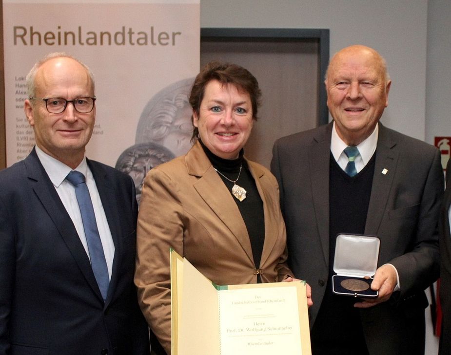 Anne Henk-Hollstein, die Vorsitzende der Landschaftsversammlung Rheinland, überreichte 2019 im Mechernicher Rathaus den begehrten Rheinlandtaler an Prof. Dr. Wolfgang Schumacher, links Bürgermeister Dr. Hans-Peter Schick. Henk-Holstein kannte den Wissenschaftler aus Antweiler bereits seit ihrer Kindheit, weil er auch mit ihrem elterlichen Bauernhof zwischen Köln und Bonn im Vertragsnaturschutz zusammenarbeitete.