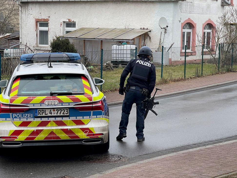 Schwerbewaffnete Polizeibeamte umstellen das Anwesen.