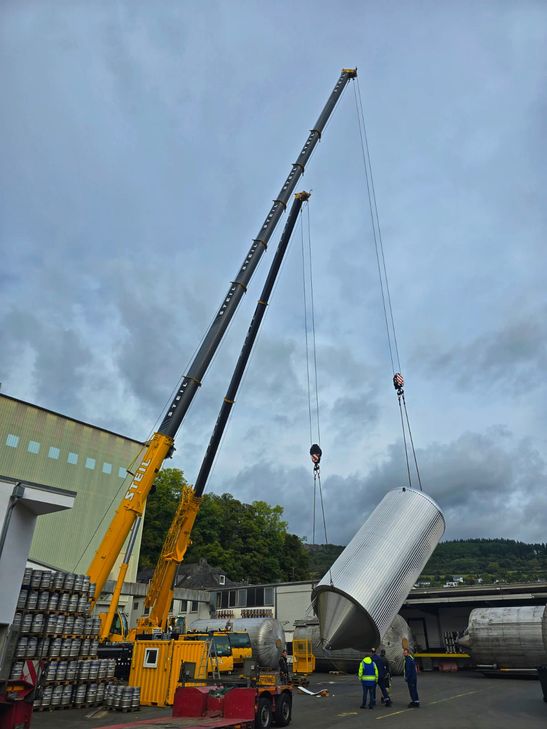 Millimeterarbeit in luftiger Höhe: Zwei Spezialkräne hieven neue Edelstahltanks in die Produktionshalle der Kirner Brauerei.