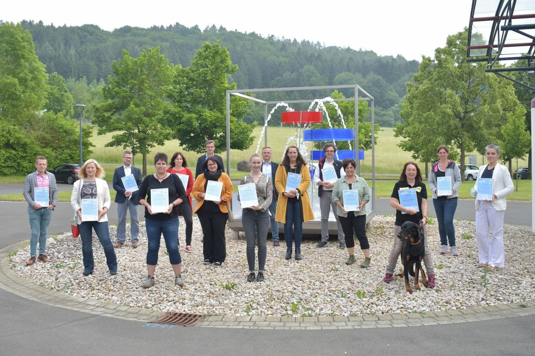 Zwei Vorstandsmitglieder des Gerolsteiner Brunnens, 13 Vertreter der »Teams mit Stern« und Hund Yuma trafen sich auf dem Werksgelände, um die Auszeichnungsurkunden des Gerolsteiner Brunnens in Empfang zu nehmen. Mit der finanziellen Unterstützung können manche der Projekte erst realisiert werden. Foto: Mager