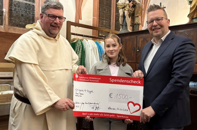 Pater Albert Seul OP und Kulturmanager Tobias Marenberg übergeben den symbolischen Spendenscheck über 1.500 Euro an Lara Hahn für ihre gemeinnützige Initiative "origami4hope".