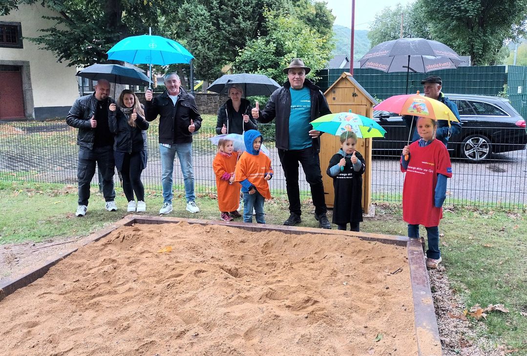 Ortsbürgermeister Guido Galle freut sich gemeinsam mit Eltern und Kindern über den frisch sanierten Spielplatz.