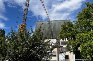 Mit einem 80 Tonnen schweren Kran werden am Theater Trier die alten Kupferfassaden des Bühnenturms entfernt. Anschließend soll der Turm mit Photovoltaik-Elementen verkleidet werden.