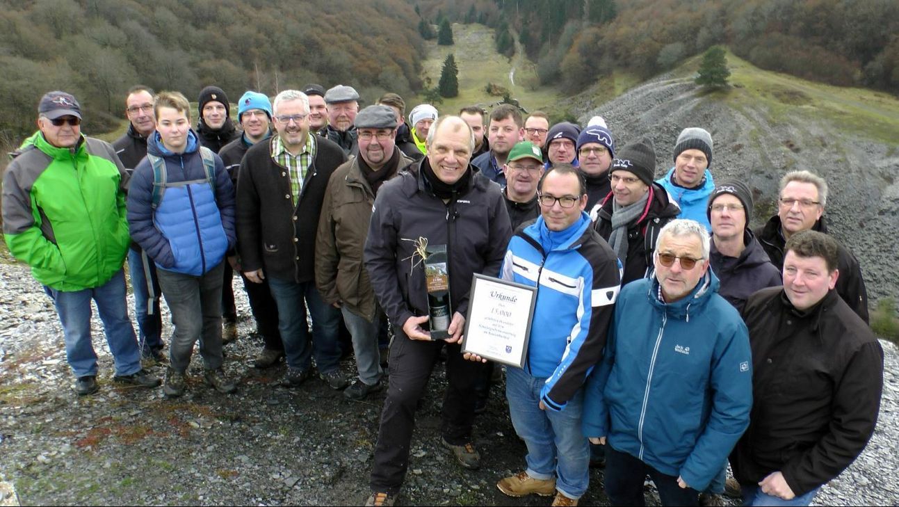 Sascha Irmiter aus Kaifenheim (mit Urkunde) inmitten seiner Feuerwehrkameraden, der durch VG-Bürgermeister Albert Jung, die Ortsbürgermeister von Laubach, Müllenbach und Leienkaul sowie den Wanderführer und Vereinsvorsitzenden Dieter Laux als 15.000. geführter Wanderer geehrt wurde.