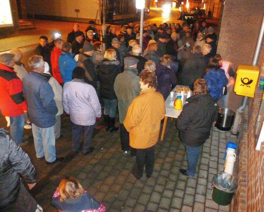 Menschen finden zusammen, singen, erzählen und erfreuen sich an schön geschmückten Adventsfenstern.