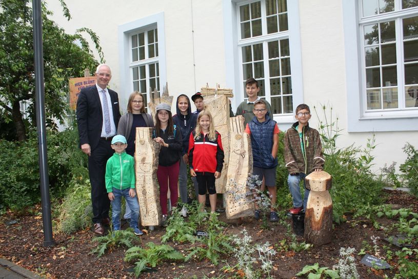 Die Rathaus Kids zeigen OB Wolfram Leibe (l.) die von ihnen bearbeiteten Baumstämme, in die demnächst Wildbienen einziehen sollen. Foto: Presseamt Trier