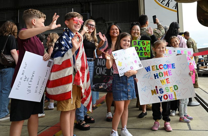 „Welcome Home“: Familien und Kinder begrüßen die zurückkehrenden Airmen der Spangdahlem Air Base mit Plakaten, Flaggen und großer Freude.