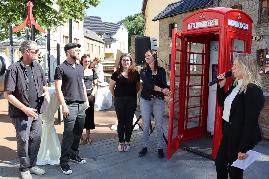 Mit den Fotografen Georg Wessel (v.l.) und Benjamin Fahl, den Mitarbeiterin der Tourist-Info Lea Schmitten, Michaela Kirchner, Sonja Aufdermauer sowie vielen weiteren Gäste feierte Bürgermeisterin Sabine Preiser-Marian (r.) der offizielle Eröffnung der neuen, roten Telefonzelle.