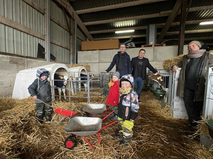 Die Kinder sind mit Eifer dabei, die Ställe der Kälber auszumisten. Bürgermeister Jan Lembach (mitte, v.li.), Fabian Koch, in der Gemeindeverwaltung für Kindergärten und Schulen zuständig, sowie Julia Krause vom Kindergarten schauen zu.