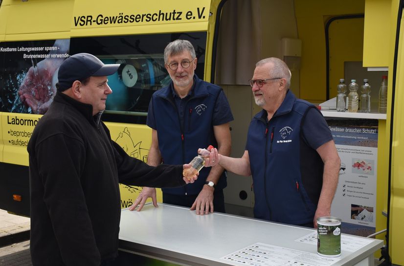 Heinz Theo van Wickeren und Harald Guelzow nehmen eine Wasserprobe entgegen.
