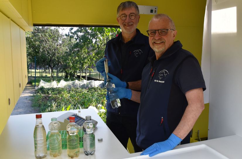 Heinz Theo van Wickeren und Harald Guelzow untersuchen eine Brunnenwasserprobe.