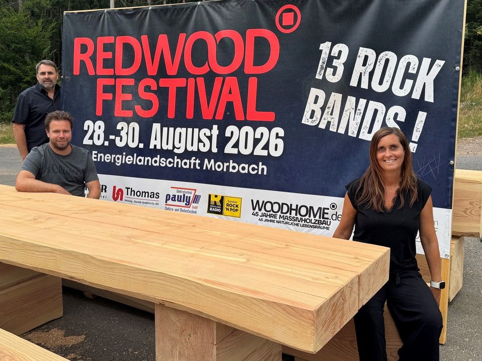 Freuen sich darauf, dass es nach vielen Monaten der Planung und Vorbereitung am 28. August losgeht: Dr.Carl Timo Manz (stehend), Jonas Herrmann und Isabelle Rosell-Manz. Die Massivholztische und Bänke wurden eigens für  den Streetfood-Bereich auf dem Festival gebaut.