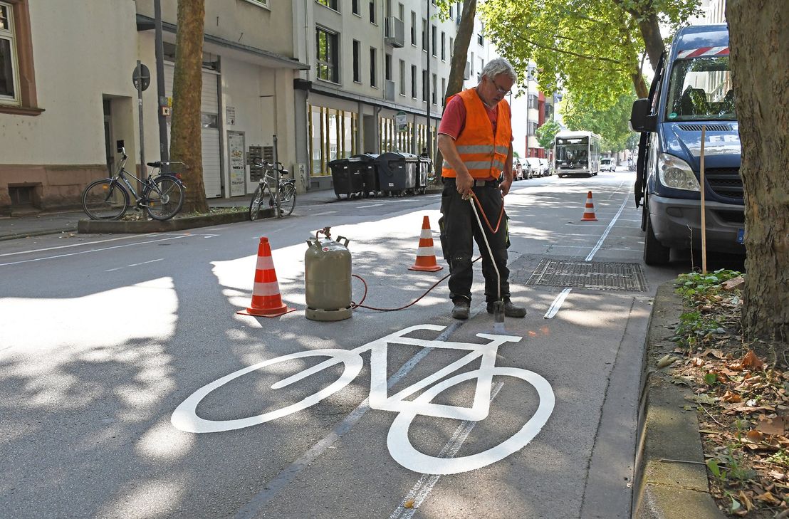 Winfried Hennen vom Trierer Bauunternehmen Franken bringt mit einem Gasbrenner eines von fünf Fahrradpiktogrammen auf die Fahrbahn der Bruchhausenstraße auf. Verbunden mit einem Richtungspfeil signalisieren sie, dass der Radverkehr gegen die Richtung der Einbahnstraße fahren darf.