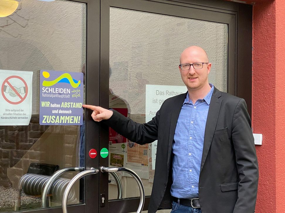 Auf den Kampagnen-Aufkleber am Eingang des Rathauses Schleiden  weist Bürgermeister Ingo Pfennings hin. Foto: Stadt Schleiden/Kerstin Wielspütz