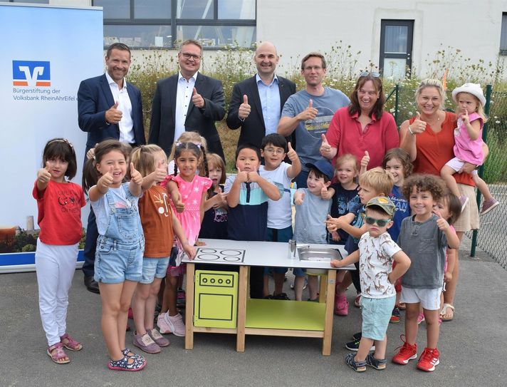 Freuen sich darüber, die ersten Spielgeräte auszuliefern (vl.): David Ackermann von der DZ Privatbank, Leiter Private Banking der Volksbank RheinAhrEifel Christian Süß und Stiftungsmanager Christof Bürger, überreichten Stefan Ibs (Leiter Kiga) den Kindergärtnerinnen und Kindern die erste Matschküche.