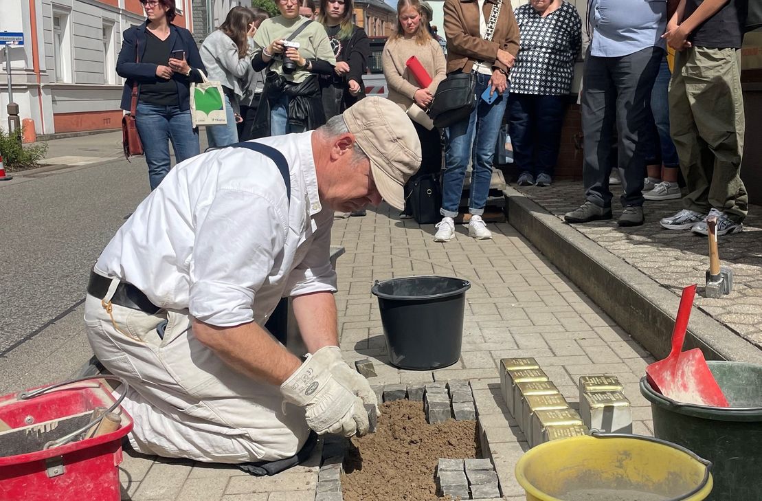 Für den erkrankten Gunter Demnig setzt sein Assistent Frank-Matthias Mann die Stolpersteine in den Gehweg ein.