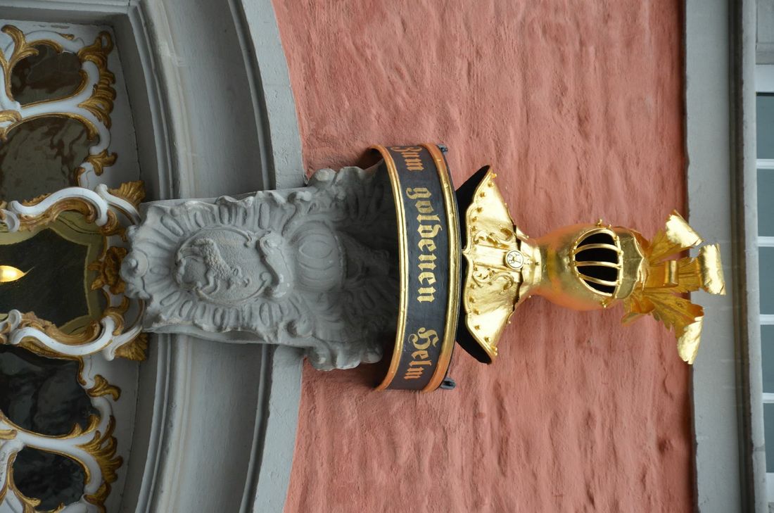 Als es noch keine Straßennamen und Hausnummern gab, behalfen sich die Menschen mit anderen Mitteln, um ihr Haus zu kennzeichnen. Sie malten Zeichen an ihren Hauseingang. Wer es sich leisten konnte, ließ sich eine Figur bildhauern - so wie die Scheiblers - oder wenigstens mit Stuck ein Zeichen. Gerade an Geschäftshäusern wurden die Hauszeichen immer kunstvoller - sie sollten den Status der Bewohner nach außen sichtbar machen.