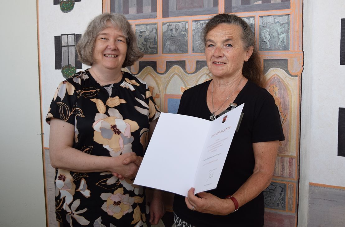 Leiterin der JVA Trier Sabine Beckmann (links) überreicht die Dankesurkunde Maria-Magdalena Reusch-Lamacz (rechts).