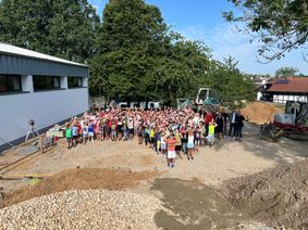 Die Kinder der Gemeinschaftsgrundschule Sistig freuen sich gemeinsam mit der Schulleitung, Gemeindevertretern und Vertretern des Fördervereins auf den neuen Soccer-Court. Die Arbeiten auf der Baustelle sind in vollem Gange.