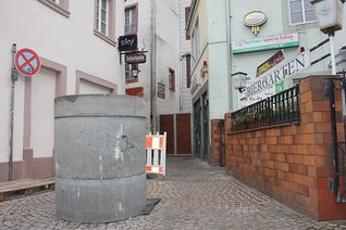 Ein Betonelement steht bereits in der Judengasse. Eine schwarze Bodenmatte verhindert das Verrutschen. Als weiteres Schutzelement wird am obersten Ring noch ein reflektierender Streifen angebracht, damit Radfahrer im Dunkeln die Barriere rechtzeitig sehen. Foto: Presseamt Stadt Trier