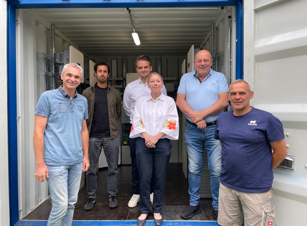 Sportdezernentin Britta Weizenegger (Mitte) sah sich gemeinsam mit Matthias Ulbrich (Abteilungsleiter Sport), Nadir Pieper, Dr. Philip Schmit (beide SWT, Abteilung Erneuerbare Energien), Achim Junk (Leiter Sportserviceteam) und Sascha Quint (Platzwart, v. l.) den Batteriespeicher für die neue Photovoltaikanlage im Moselstadion an.