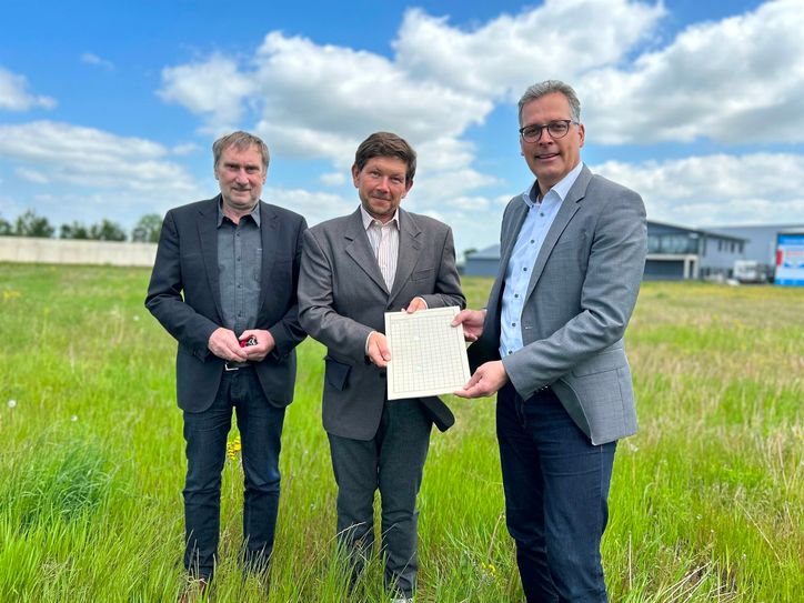 Beim Ortstermin auf dem Grundstück an der Römerallee übergaben Bürgermeister Ulf Hürtgen (re.) und der Beigeordnete und Kämmerer Ottmar Voigt (l.) die Baugenehmigung zur Errichtung eines McDonald’s-Restaurants an Projektmanager Matthäus Zaik.