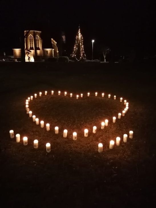 Ein von Händen getragenes Herz aus Grablichtern hat Beate Mack an mehreren Plätzen in der Gemeinde Simmerath aufgestellt, um an die Verstorbenen der Corona-Pandemie zu erinnern. Foto: Beate Mack