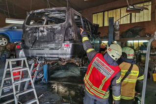 Mit einer Wärmebildkamera überprüfte Einsatzleiter Nils Heidrich (rechts) das abgebrannte Fahrzeug auf der Hebebühne.