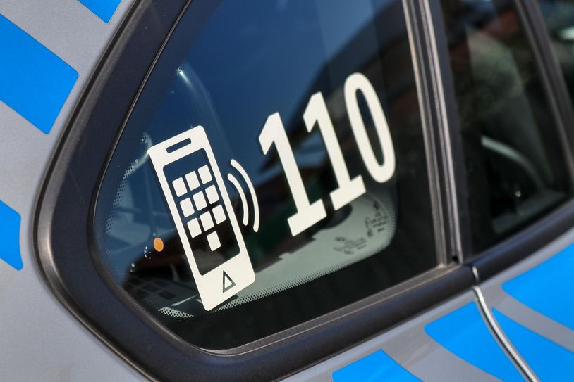 Symbolfoto eines Autofensters mit der Polizei-Notrufnummer 110 darauf.