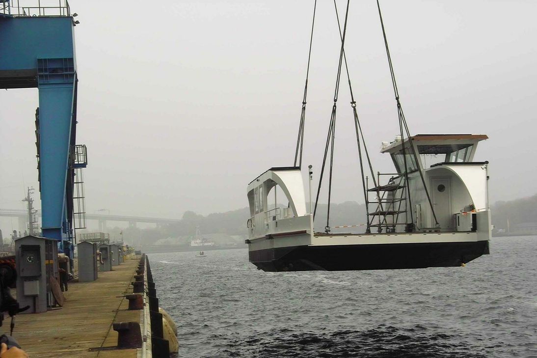 Zwei Krane hievten die Elektro-Solar-Autofähre in Stralsund ins Wasser....