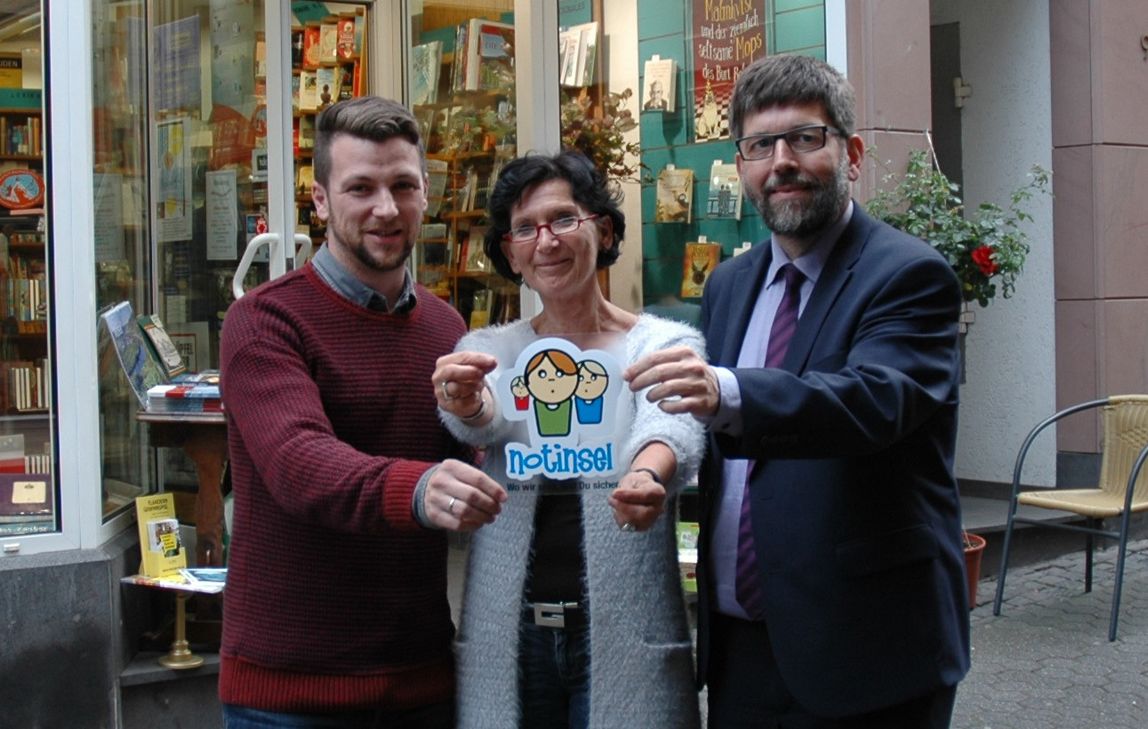 Die Buchhandlung Layaa-Laulhé ist eine der ersten "Notinseln" in Cochem. Der Sticker wurde kürzlich im Schaufenster angebracht v.l.: Thomas Theiß, Cornelia Layaa-Laulhé und Wolfgang Lambertz.