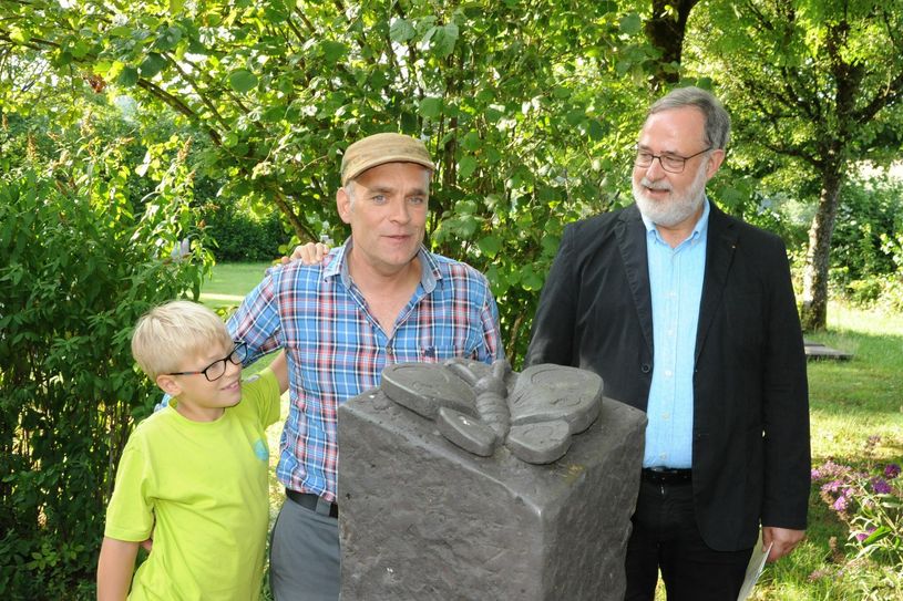 Hospizvereins-Vorsitzender Detlef Willems (r.) mit Steinmetz Hennig Wirtz und dessen Sohn an der Stele mit dem Schmetterling, einer von dreien am Weg der Erinnerung auf dem Hermeskeiler Friedhof. Foto: Schmieder