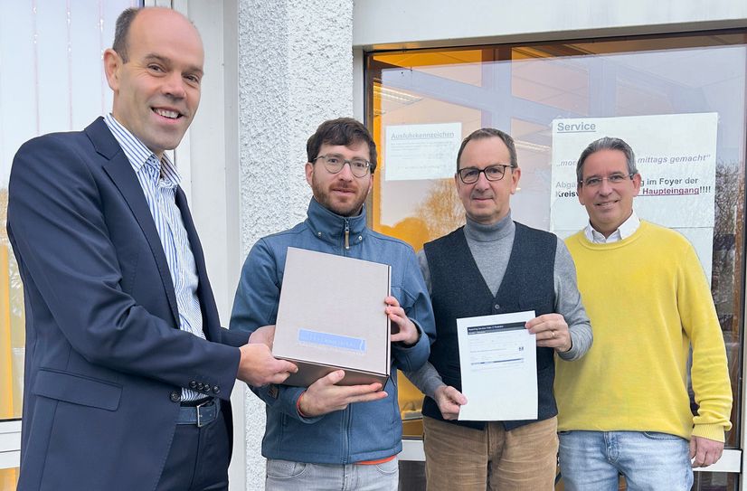 V.l.: Landrat Volker Boch gratuliert dem Jubilar Frank Reuter, dem Fahrzeughalter des 2000. vollelektrischen Kraftfahrzeugs im Rhein-Hunsrück-Kreis. Ebenfalls gratulierten der Leiter des Fachbereichs Straßenverkehr und KFZ-Zulassung Andreas Schmidt sowie Klimaschutzmanager Frank-Michael Uhle.
