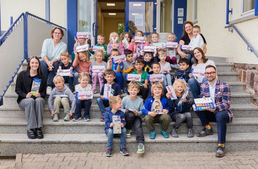 Johannes Habscheid (rechts unten) und Lea Casper, Kundenberaterin (links unten) übergaben die Malkästen im Beisein der Schulleiterin Alexandra Hoch (links oben) an die Schüler der Grundschule am Waldsee in Argenthal.