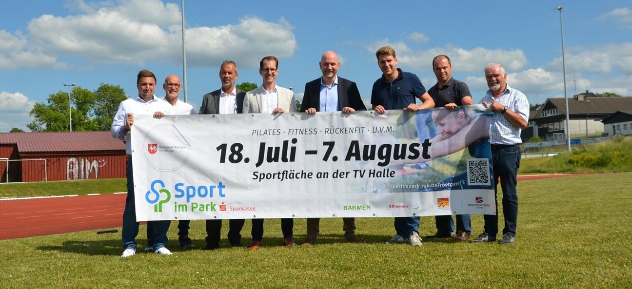Vertreter von Regiosportbund, Gemeinde Roetgen, TV Roetgen, BARMER und Sparkasse Aachen freuen sich auf das kostenfreie und niederschwellige Angebot »Sport im Park« auf der Sportfläche zwischen TV-Halle und FC-Kunstrasenplatz inmitten von Roetgen.