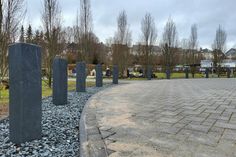 Im Halbkreis sind zehn freistehende, anthrazitfarbene Stelen aus Naturstein angeordnet.
