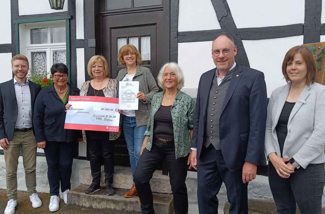 Ein Spendenscheck über 50.000 Euro und zufriedene Gesichter vor dem Lammersdorfer Bauernmuseum: Daniel Scheen-Pauls (MDL), Sabine Verheyen, Edith Laeven, Astrid Hermanns, Elisabeth Paul, Andreas Hermanns, Jennifer Stollenwerk.