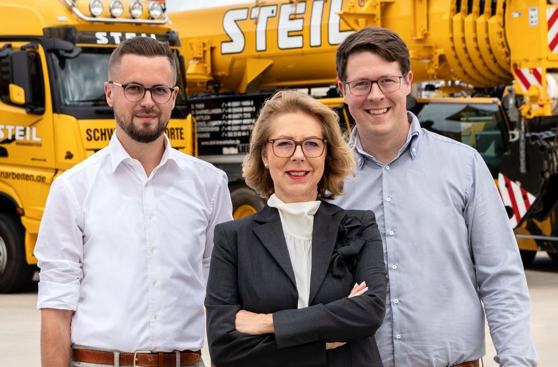 "Steil Kranarbeiten" feiert 100-Jähriges. Seit 1989 leitet Birgit Steil (Mitte) das Unternehmen, seit 2022 mit ihren Söhnen Christopher Steil (links) und Daniel Gödert (rechts) in der Geschäftsführung.
