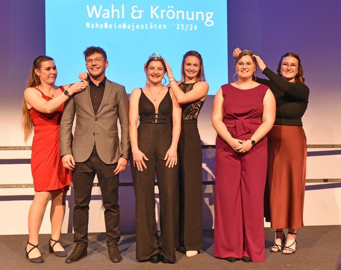 Glücklicher Moment: Die bisherige Naheweinkönigin Christina Schwarz (3. v. r.) setzt ihrer Nachfolgerin Katharina Gräff (3. v. l.) die Krone ins Haar, während Johanna Lorenz (r.) Jana Blum krönt und Tina Anheuser (l.) Tim Heck die schmucke Brosche des Weinprinzes ans Revers heftet.