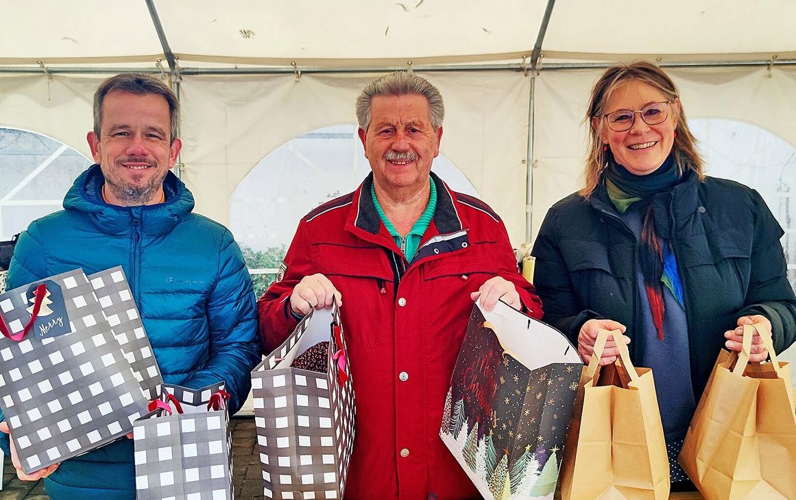 Martin Jost (v.li., Vorstand Caritas), Hubert Hamacher und Maria Surges-Brilon (Vorstand Caritas) bei der Ausgabe der Weihnachtstüten. Foto: Carsten Düppengießer