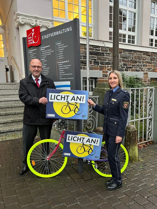 Polizeirätin Kimberly Short und Bürgermeister Friedrich Marx präsentieren eines der Fahrräder, die im Rahmen der Aktion ‚Licht an!‘ im Stadtgebiet aufgestellt werden.