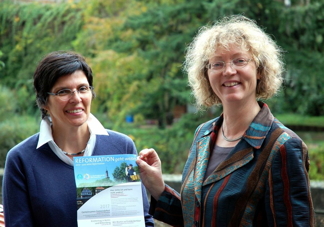 Pfarrerin Decker-Ruppert (links) und Pfarrerin Weiser (rechts) mit dem Flyer zum Jahresprogramm der Ev. Kirchengemeinde.
